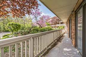 A balcony with a railing and a view of a garden and houses.