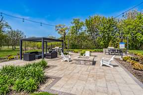 A sunny day at the park with a gazebo, chairs, and a picnic table.