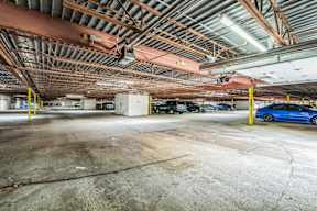 A blue car is parked in a large, empty parking garage.