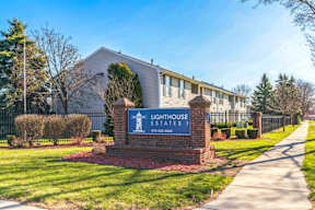 The image shows the entrance to Lighthouse Estates with a sign and a building in the background.