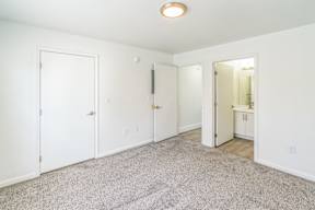 A white room with a carpeted floor and a door on the left.