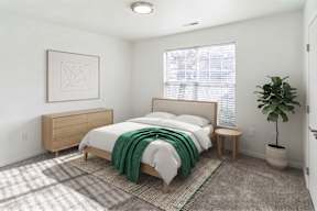 A bedroom with a bed, nightstand, and a potted plant.