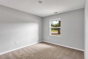 Spacious bedroom with carpet and window at Arbor Crossings Muskegon MI