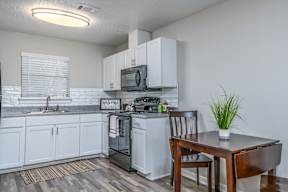 Auburn kitchen with white cabinets and a wooden dining table