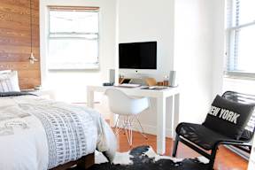 a bedroom with a bed and a desk in front of a window