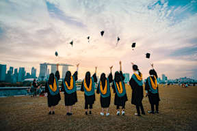 a group of women in graduation gowns throwing graduation caps in the air