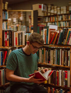 a young man reading a book in a library