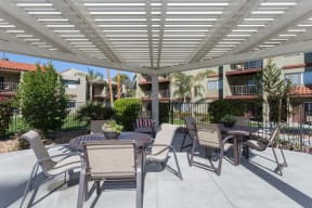 a patio with tables and chairs under a shade