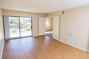 an empty living room with wood flooring and sliding glass doors