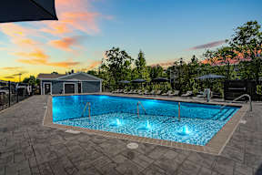 A large outdoor swimming pool with a sunset sky in the background.