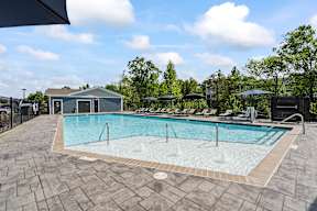 A large outdoor swimming pool surrounded by a stone patio.