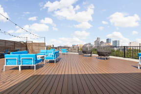 a roof top patio with blue chairs and a fire pit