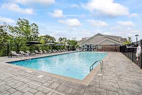 A pool surrounded by a black fence and a building in the background.