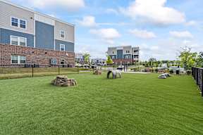 A grassy area in front of a building with a fence on the left side.