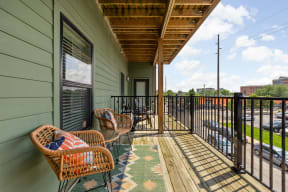 a balcony with wicker chairs and a view of the indianapolis at the vue apartments