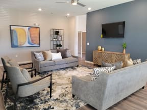 Clubhouse with empty couches and chairs with tv on the wall at Promenade Luxury apartments in Beaumont, Texas