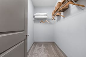 a walk in closet with a gray door and a closet organizer with white pillows