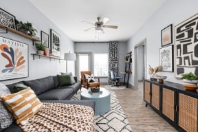 a living room with a gray couch and a blue coffee table and a ceiling fan