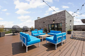 a rooftop patio with blue chairs and a brick building at the vue apartments in indianapolis