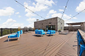 the deck on the top of the vue apartment building with blue chairs