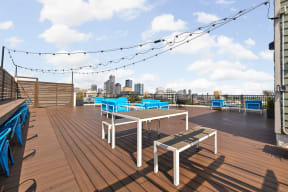 a rooftop deck with tables and chairs and a view of indianapolis in the background