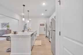 a white kitchen with a marble counter top and white appliances at spire apartments in charlotte nc