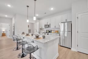 a large kitchen with an island with bar stools and a stainless steel refrigerator at spire luxury apartments in charlotte nc