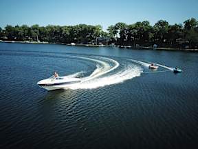 A speedboat is cutting through the water leaving a wake behind it.