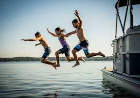 Three people jumping into the water from a boat.