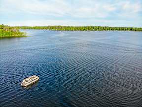 A boat is sailing on a lake with trees on the shore.