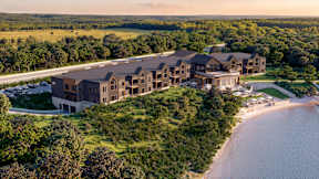 A large building complex is situated on a beachfront with a body of water in front of it.