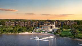 A modern residential complex is situated on the shore of a calm body of water.