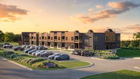 A modern apartment complex with a parking lot in front.