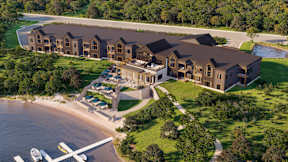 A large building complex with a dock and boats in front of it.