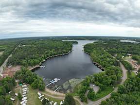 A large lake surrounded by greenery and a cloudy sky.