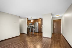 an empty living room and kitchen with a wood floor and white walls