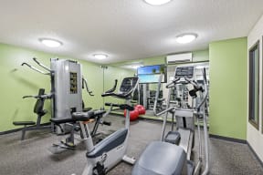 a gym with exercise equipment and green walls