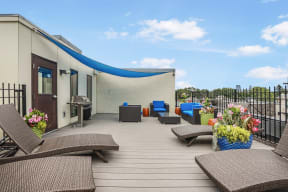 a rooftop deck with chairs and a grill and a blue roof