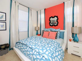 a bedroom with a bed and a red wall and white curtains at The Vines at Riverpark, LLC, Oxnard, CA 93036