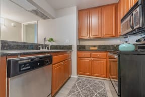 a kitchen with stainless steel appliances and wooden cabinets at City View Apartments at Warner Center, Woodland Hills, CA