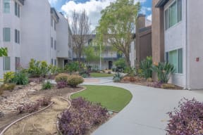 an exterior view of an apartment building with a sidewalk and grass at City View Apartments at Warner Center, California