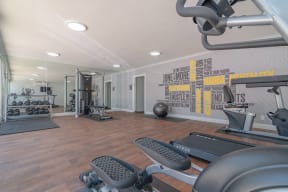 the gym is equipped with exercise machines and weights at The Flats on Addison, Sherman Oaks