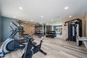 A spacious gym with a variety of equipment including treadmills, stationary bikes, and weight machines at Latitude Apartments at Mission Valley Apartments, San Diego, 92120