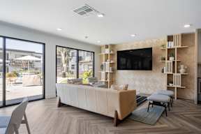A modern living room with a large sofa and a flat-screen TV mounted on the wall at Latitude Apartments at Mission Valley Apartments, San Diego, CA, 92120