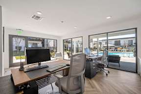 A modern office with a view of a pool and trees outside the windows at Latitude Apartments at Mission Valley Apartments, San Diego, CA