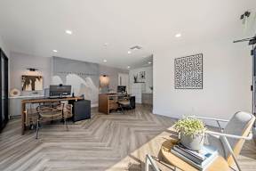 A modern office space with a wooden floor and a large desk with a laptop and a plant on it at Latitude Apartments at Mission Valley Apartments, San Diego, 92120