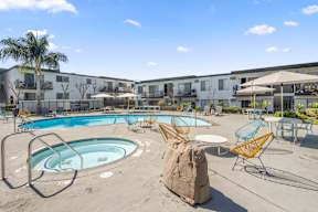 A large outdoor swimming pool with a rock in the middle of it at Latitude Apartments at Mission Valley Apartments, San Diego