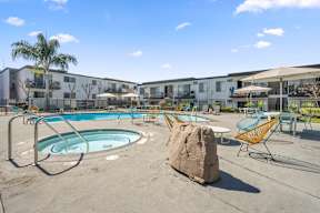 A swimming pool surrounded by chairs and a rock at Latitude Apartments at Mission Valley Apartments, San Diego, CA, 92120