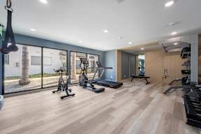 A spacious gym with a variety of equipment and a view of the outside at Latitude Apartments at Mission Valley Apartments, California