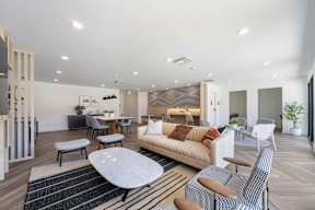 A modern living room with a white sofa, a coffee table, and a dining table at Latitude Apartments at Mission Valley Apartments, San Diego, California